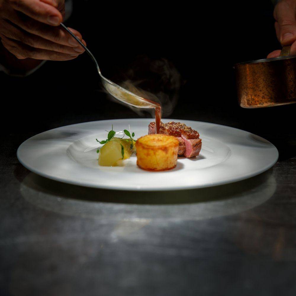 Sauce being spooned over a plated dish